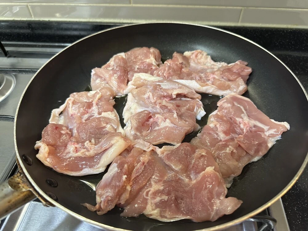 팬에 펼쳐 구워지고 있는 닭다리살 — 파에야 첫 단계