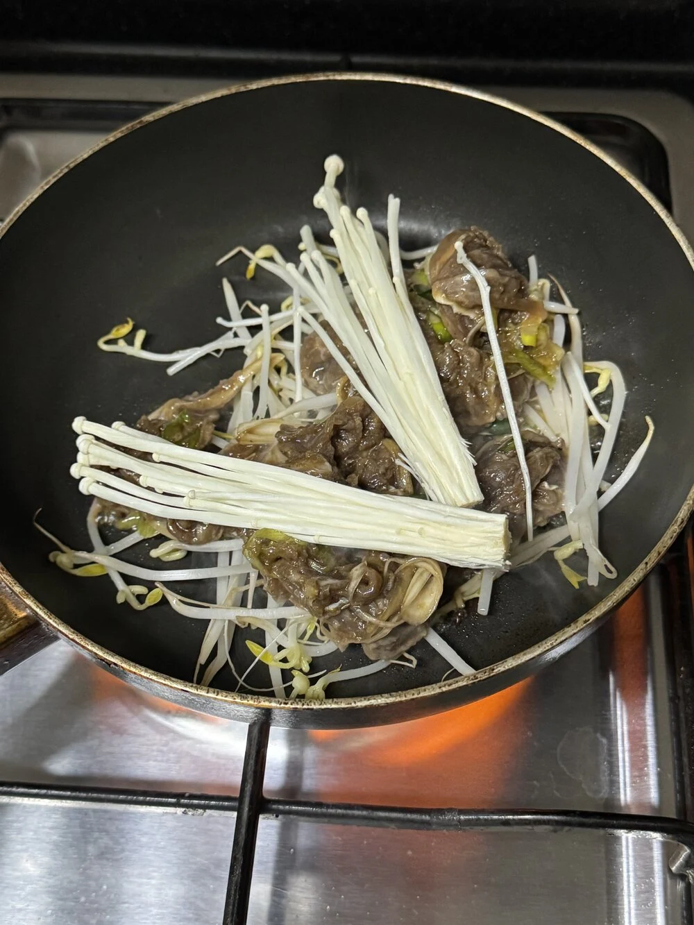 숙주 위에 불고기와 팽이버섯을 올려 아이용으로 순하게 볶는 장면