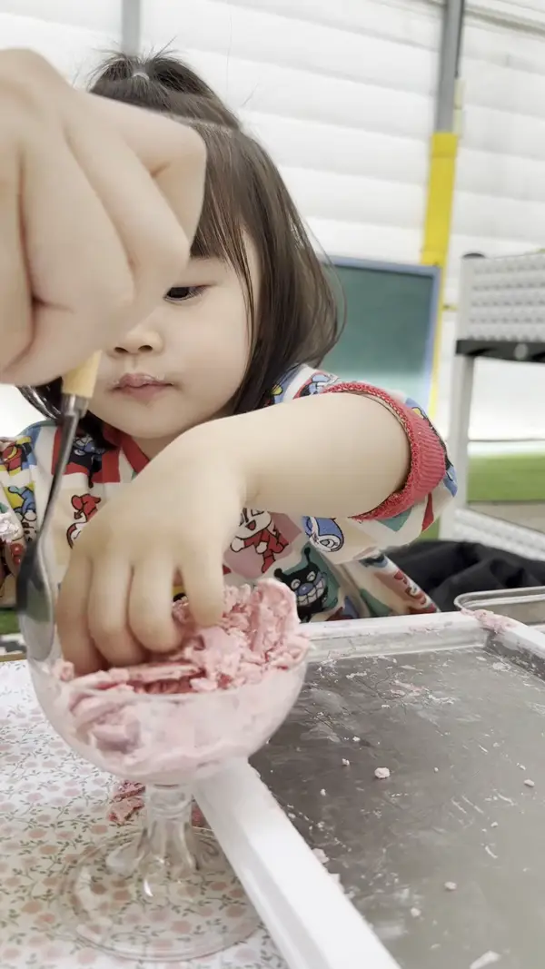 自分で作ったいちごアイスクリームを食べる子ども