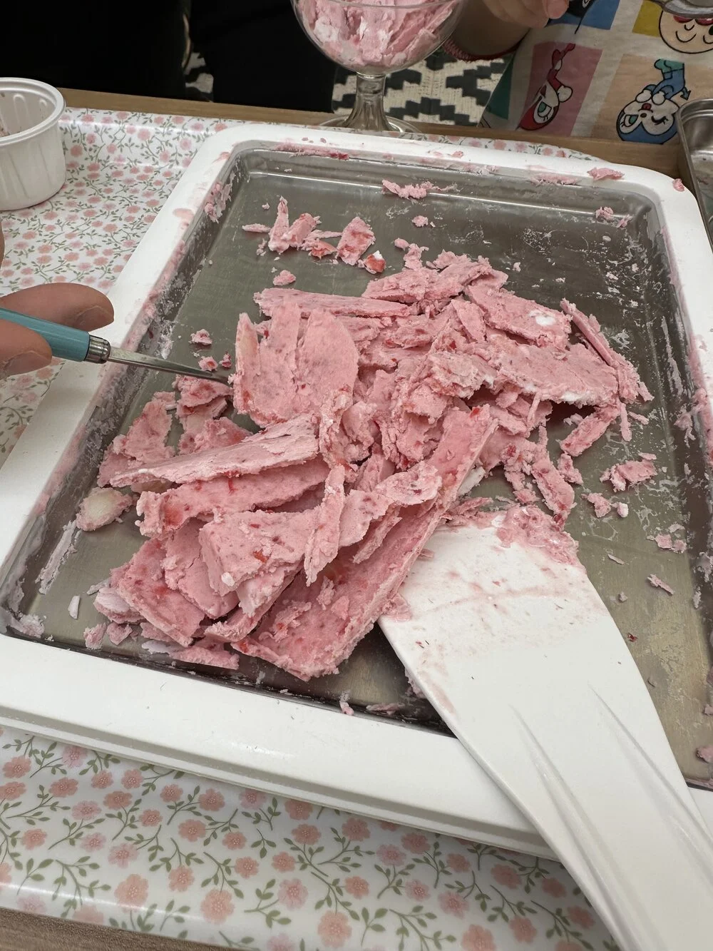 冷たい鉄板で固まったいちごアイスクリームを削っている様子